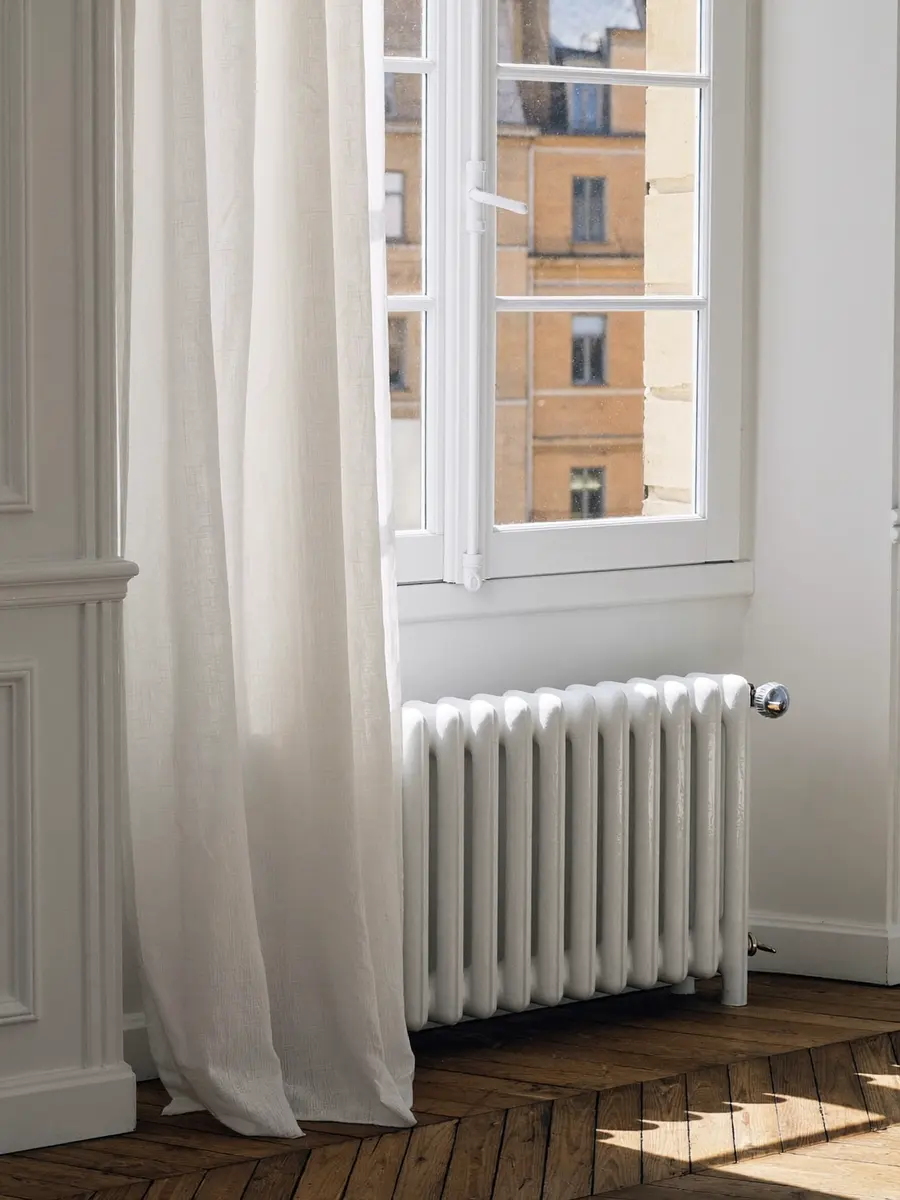 Radiateur blanc sous une fenêtre ensoleillée